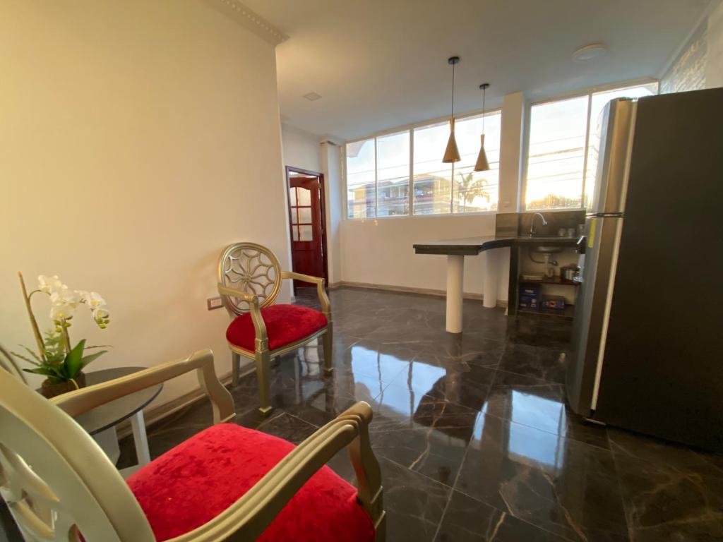eine Küche und ein Wohnzimmer mit einem Kühlschrank und Stühlen in der Unterkunft Suites AlojaT MIMOS Machala diagonal al oro verde. in Machala