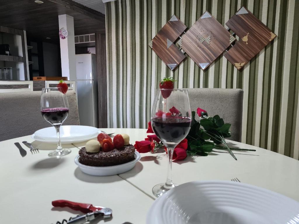 a table with two glasses of wine and a plate of food at Refugio Por do Sol - 09 Pessoas - WiFi- Ar Condicionado in Gramado