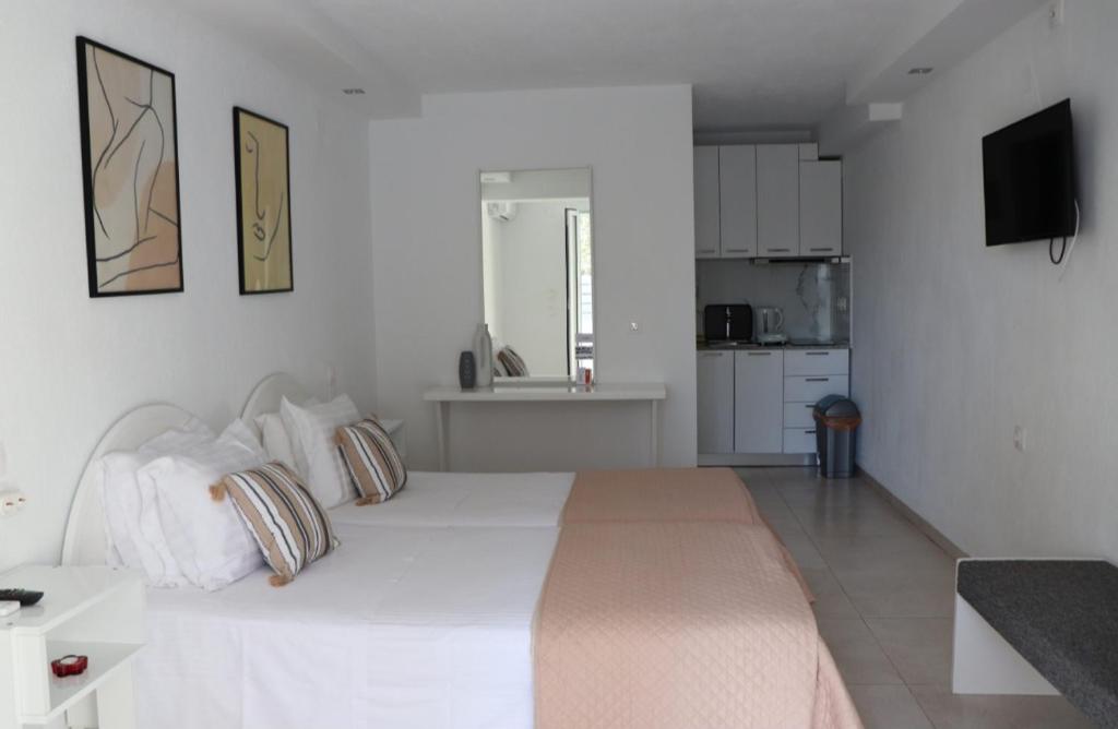 una camera bianca con un grande letto bianco con cuscini di Fiosal Apartments 2 a Città di Skiathos