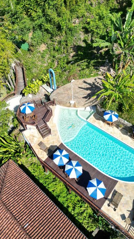 uma vista sobre uma piscina com guarda-sóis azuis e brancos em Hotel Coquille em Ubatuba