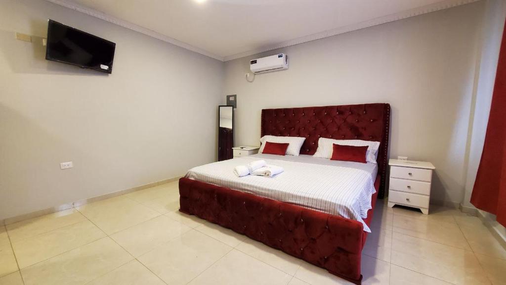 a bedroom with a large bed with a red headboard at Habitaciones AlojaT MIMOS diagonal al hotel oro verde in Machala
