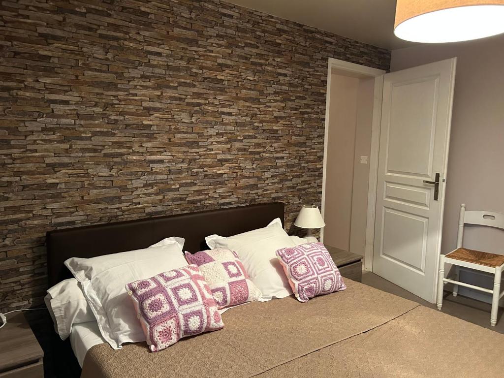 1 dormitorio con pared de ladrillo y cama con almohadas en Chambres d’hôtes chez Colombet, en Tardets-Sorholus