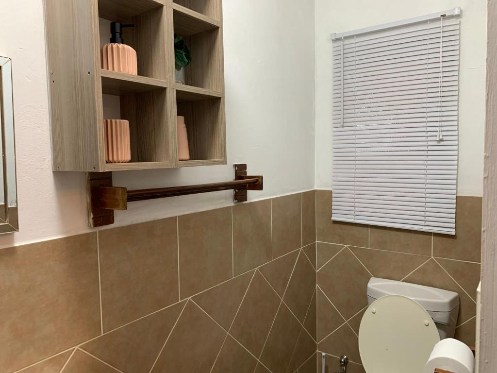 a bathroom with a toilet and a window at LuxuryAirportLodge near OR TAMBO in Kempton Park