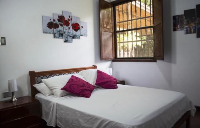 1 dormitorio con cama blanca y almohadas rosas en Habitacion Casa Campestre con piscina en Buga, 