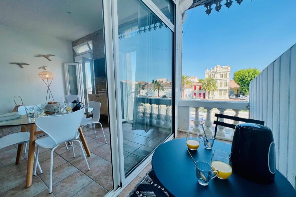 a room with a balcony with a table and chairs at Terrasse du Port -Appartement 2 chambres avec vue sur le canal in Le Grau-du-Roi