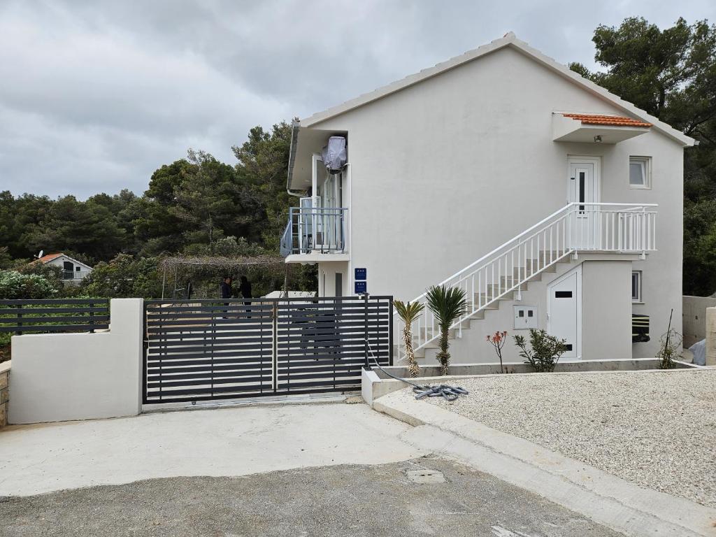 une maison blanche avec une clôture devant elle dans l'établissement Seaside holiday house Prizba, Korcula - 21583, à Blato