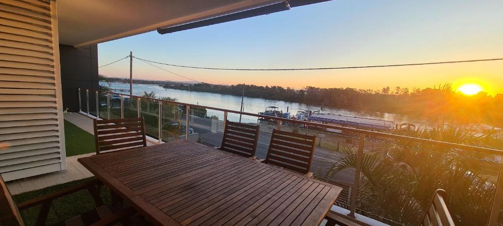 d'un balcon avec une table en bois et une vue sur la rivière. dans l'établissement Waterline 202, à Forster