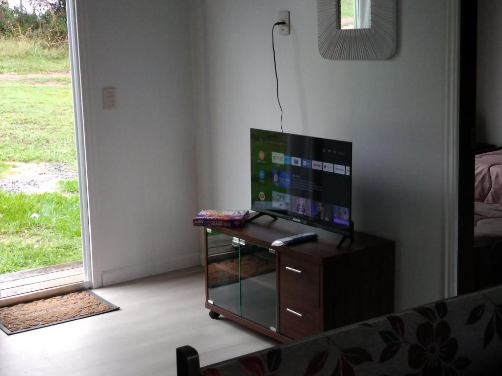 a living room with a tv and a table and a window at Casa en Villa Serrana para 4 personas. in Villa Serrana