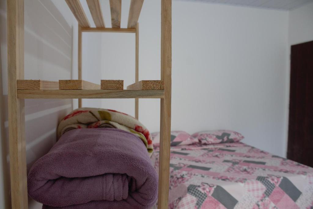 a bunk bed with a purple blanket and a shelf at Pousada Flor de Laranjeira in Lençóis