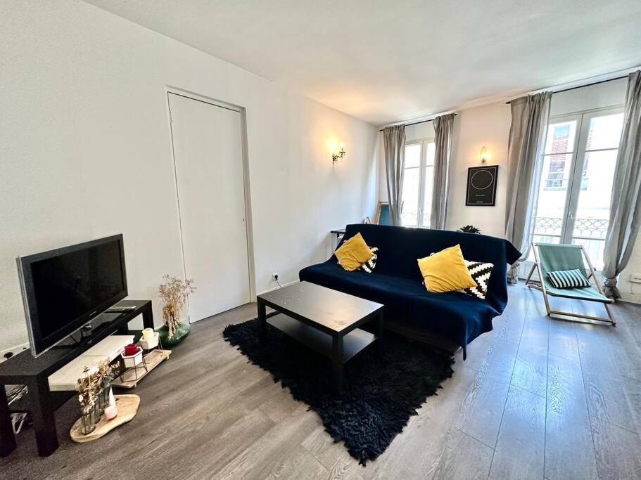 ein Wohnzimmer mit einem blauen Sofa und einem TV in der Unterkunft Cosy appartement au cœur de Nice - Clim & Parking in Nizza