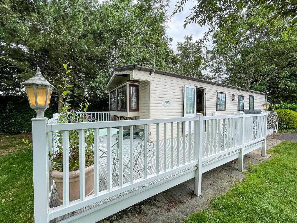 a small white house with a white fence at Superb Caravan With Decking At Southview Holiday Park Ref 33093s in Skegness