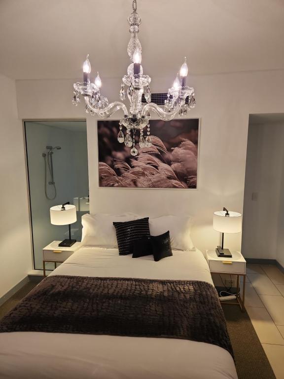 a bedroom with a large white bed with a chandelier at 1213/146 Sooning street, Nelly Bay, Magnetic Island. Qld 4819. One Bright Point. in Nelly Bay