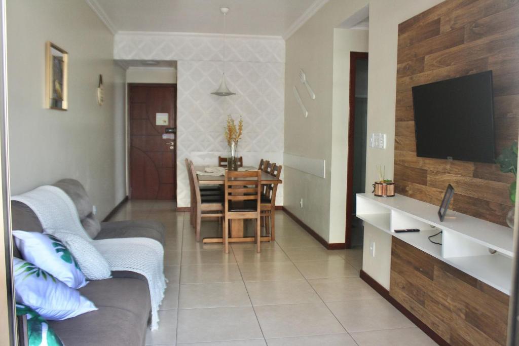 sala de estar con sofá y mesa con TV en Aconchegante 3 quartos na Prainha, en Arraial do Cabo