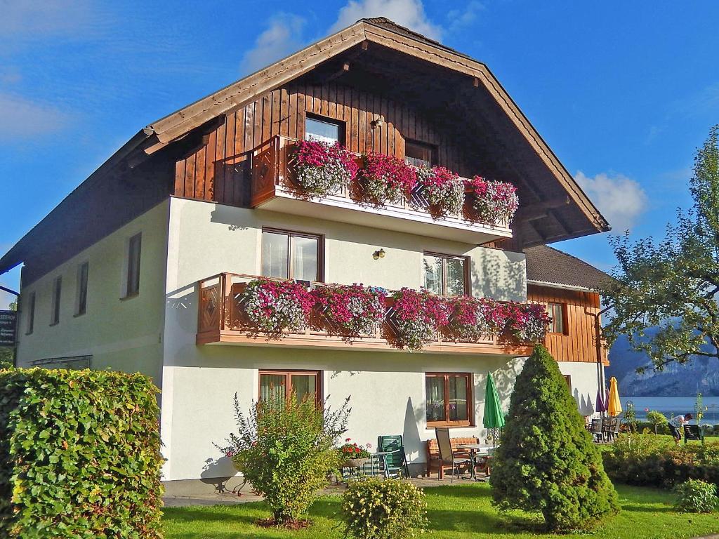 une maison avec des boîtes de fleurs sur le balcon dans l'établissement Haus Seehof, à Sankt Gilgen