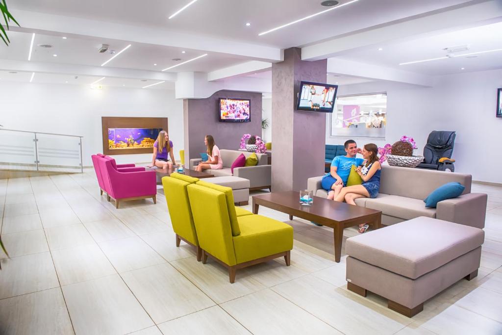 a waiting room with people sitting on couches and chairs at New Famagusta Hotel & Suites in Ayia Napa