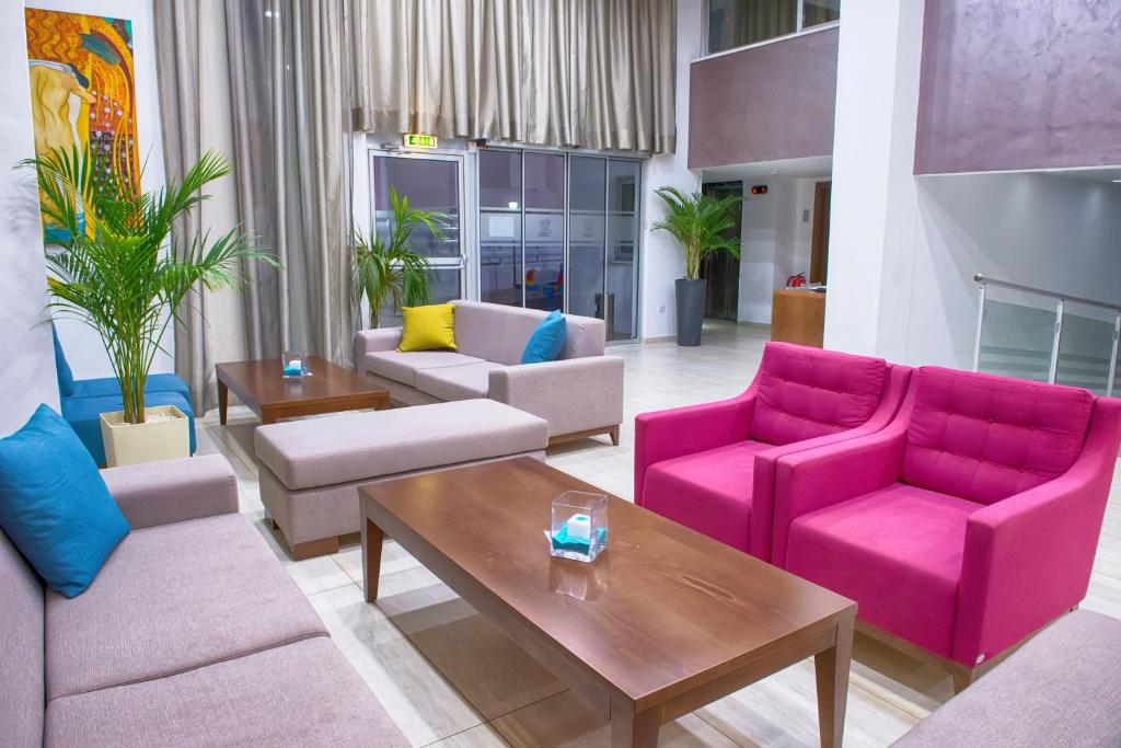 a living room with pink couches and a table at New Famagusta Hotel & Suites in Ayia Napa