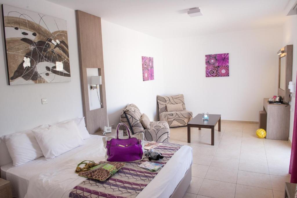 a room with a bed with a purple bag on it at New Famagusta Hotel & Suites in Ayia Napa