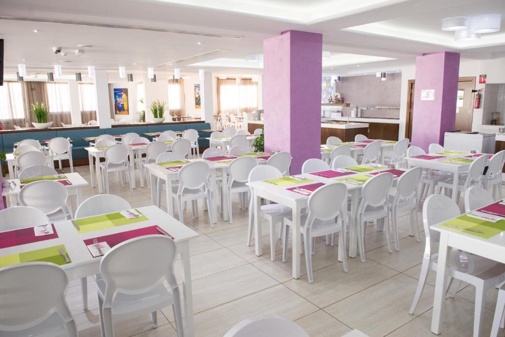 a dining room with white tables and white chairs at New Famagusta Hotel & Suites in Ayia Napa