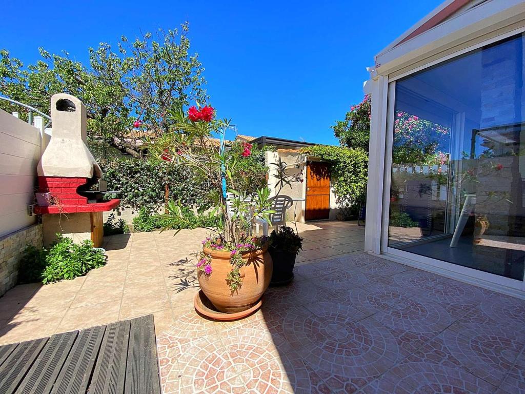 un patio avec un grand pot contenant des plantes dans l'établissement Maison PMR avec Terrasse, Clim et Parking à 900m de la Mer - 4 Couchages - FR-1-229-872, à Gruissan