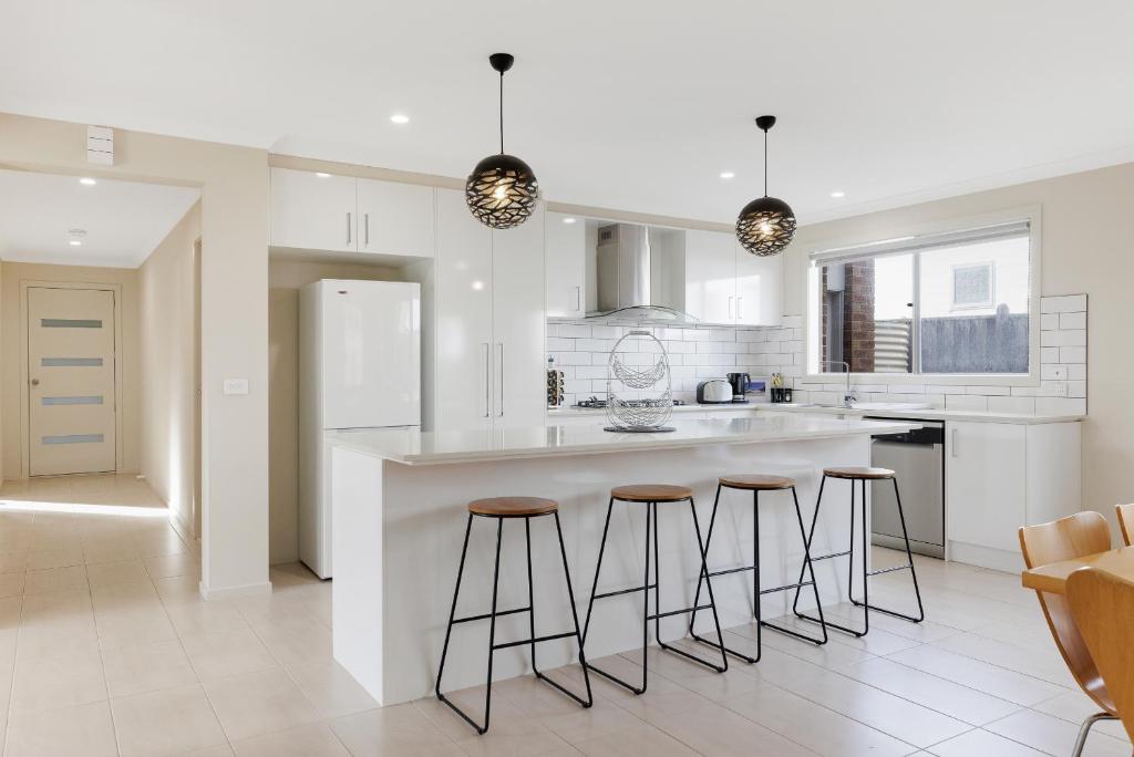 une cuisine avec un grand îlot et des tabourets de bar dans l'établissement The Grampian in Cowes BYO LINEN & TOWELS, à Cowes