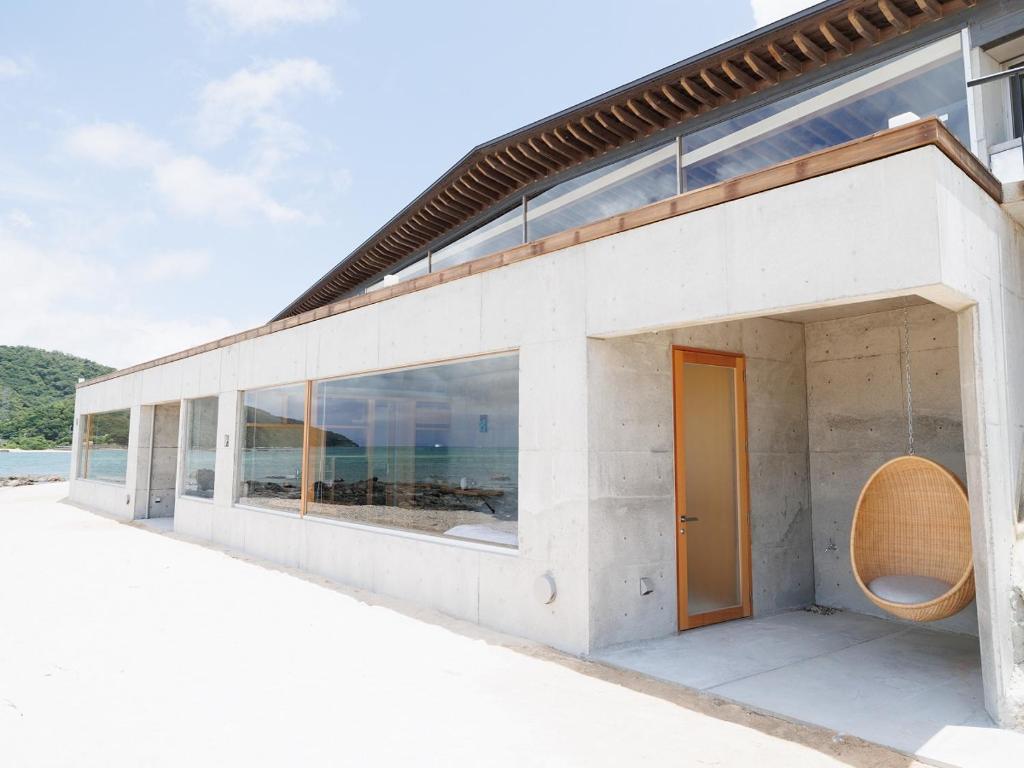 a white building with a orange door and windows at Denpaku The Beachfront MIJORA in Amami