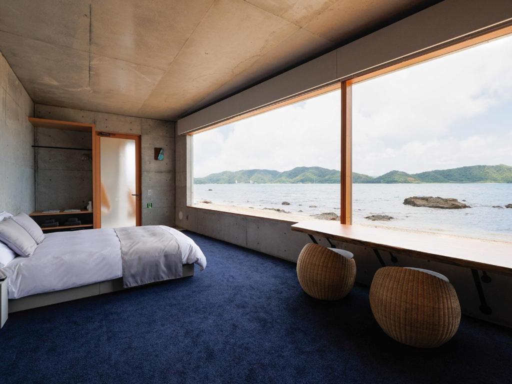 a bedroom with a bed and a large window at Denpaku The Beachfront MIJORA in Amami