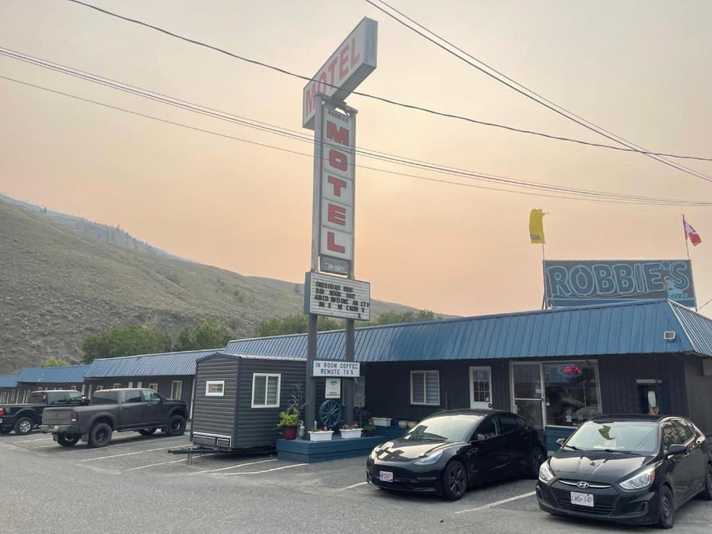 a motel with two cars parked in a parking lot at Robbie's Motel in Cache Creek