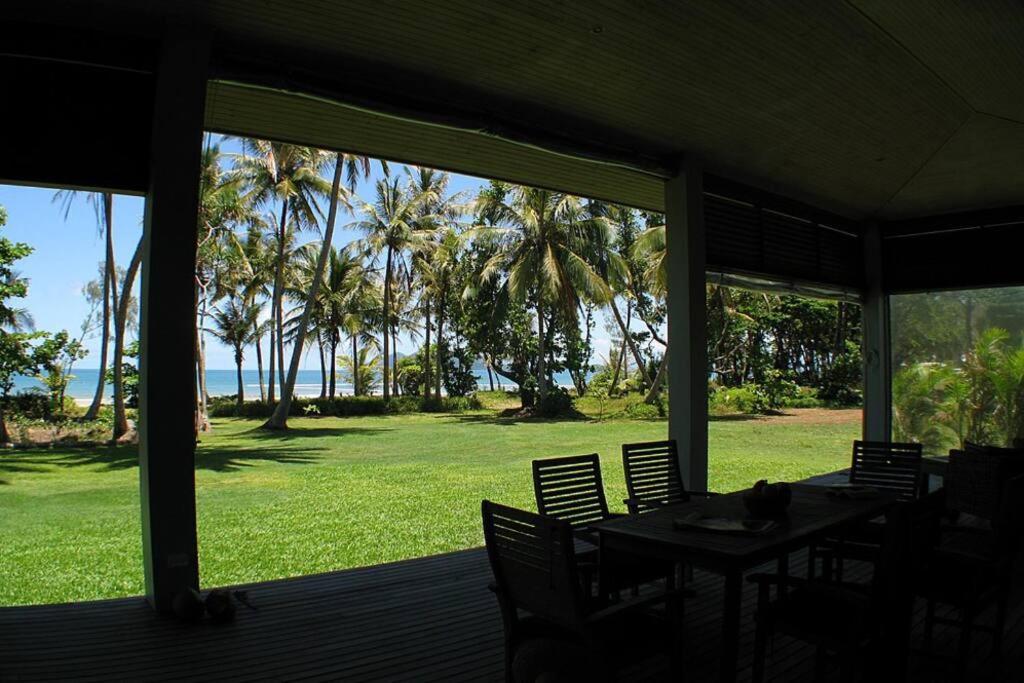 a porch with tables and chairs and a view of the ocean at Tropika - Absolute Beachfront in Mission Beach