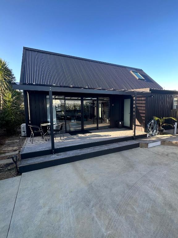 a building with a table and chairs in front of it at Modern Two bedroom Oasis in Whangamata