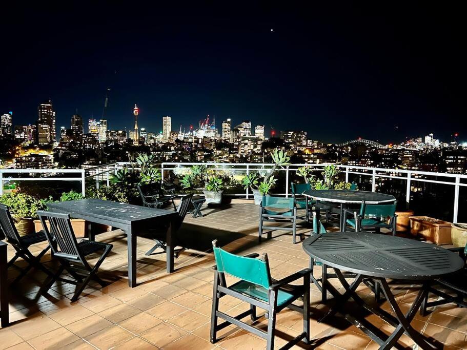 a deck with tables and chairs and a view of a city at Studio in Darling Point in Sydney