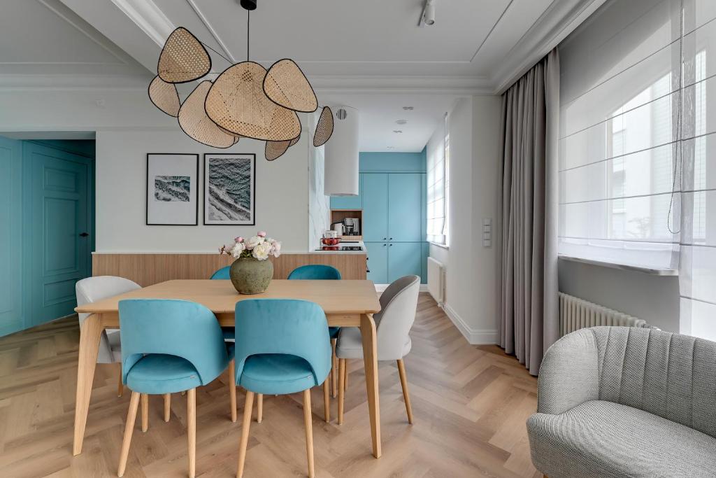 a dining room with a wooden table and blue chairs at Lion Apartments - Havana Premium Family Stay in Sopot