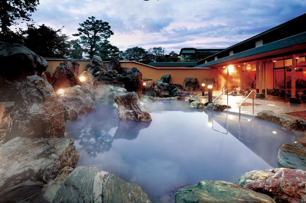 a pool of water with rocks in front of a building at Kintarou Onsen in Uozu