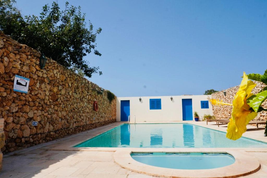 uma piscina ao lado de uma parede de pedra em Masri Accommodation em Il-Pergla