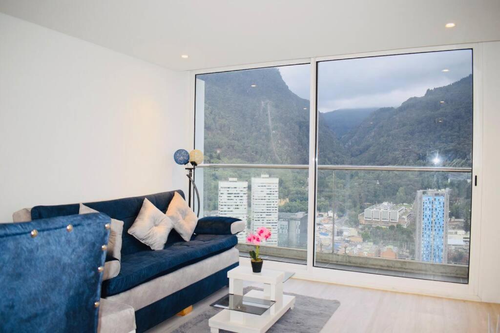 a living room with a blue couch and a large window at Apartamento piso 41 VIP Hermosa vista en Bogotá in Bogotá