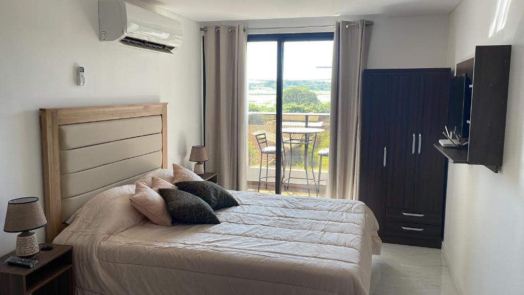 1 dormitorio con 1 cama y vistas a un balcón en Bello monoambiente a metros del aeropuerto, en Colonia Mariano Roque Alonso