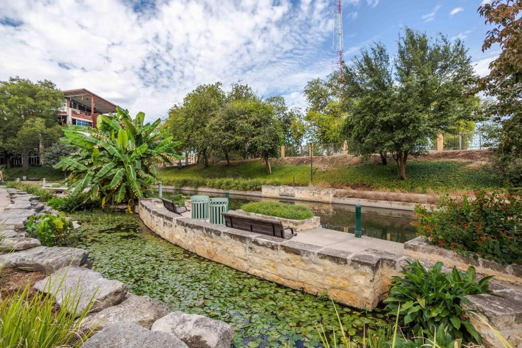 a park with a bench next to a body of water at Downtown Apartment on Riverwalk! in San Antonio