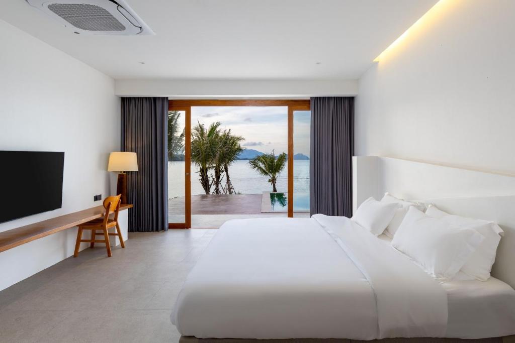 a bedroom with a white bed and a television at X-Sea Khanom Harbor Bay Resort in Ban Phang Phrao