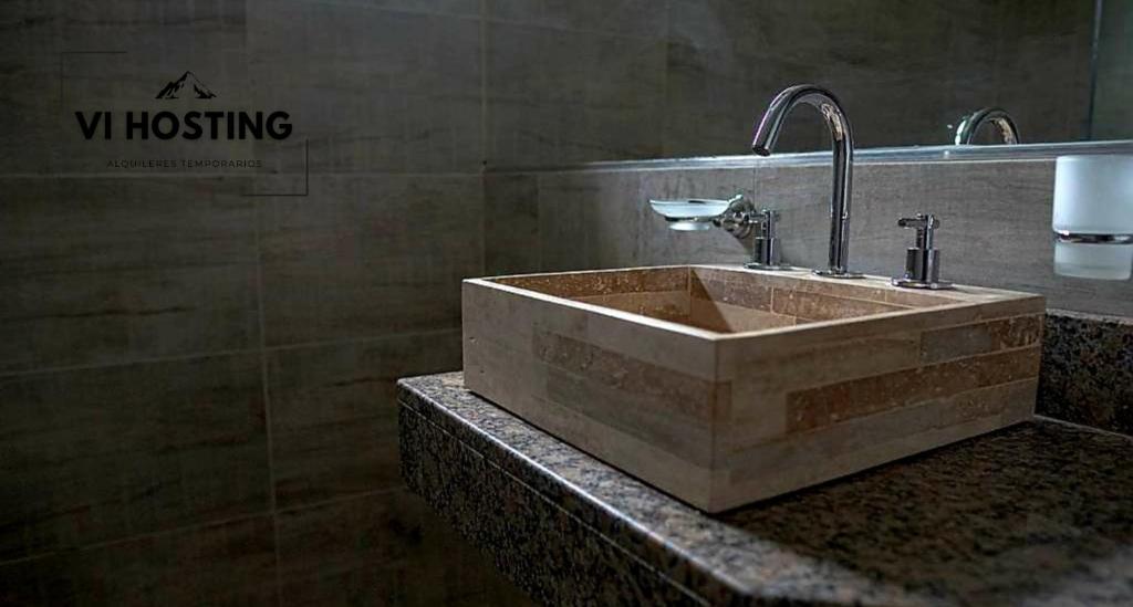 Baño con lavabo de piedra y pared en Vi Hosting Cabañas Premium en Salta