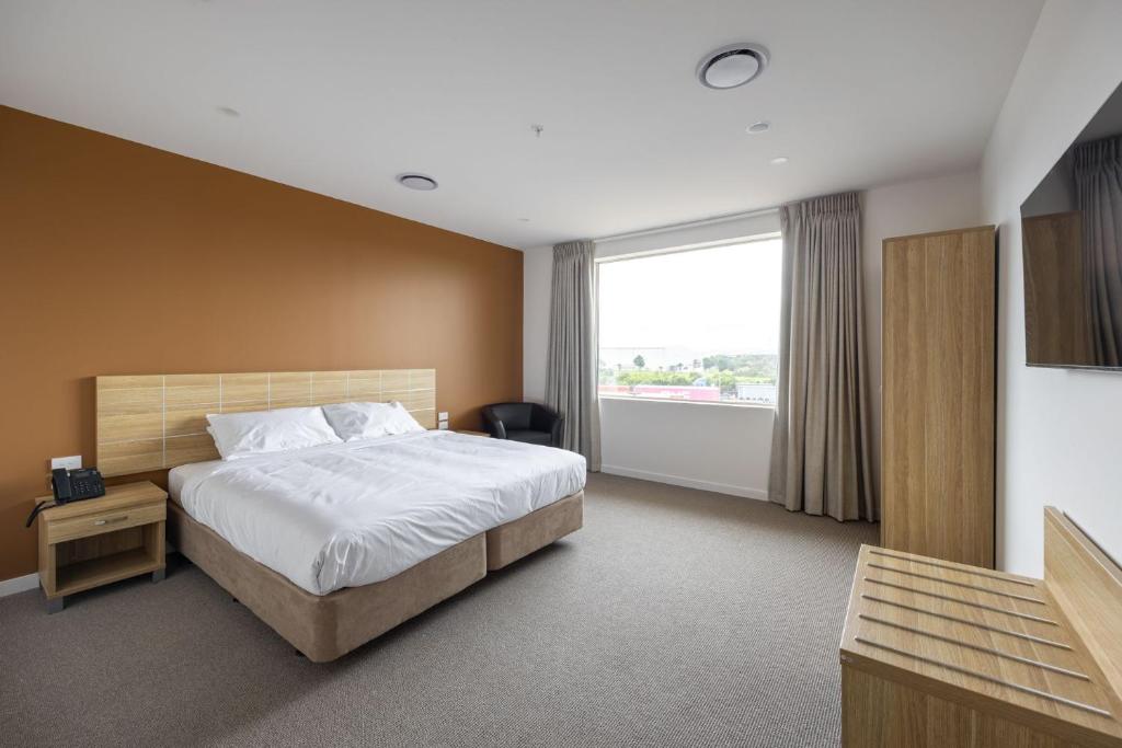 a hotel room with a bed and a large window at Manha Hotel Auckland Airport in Auckland