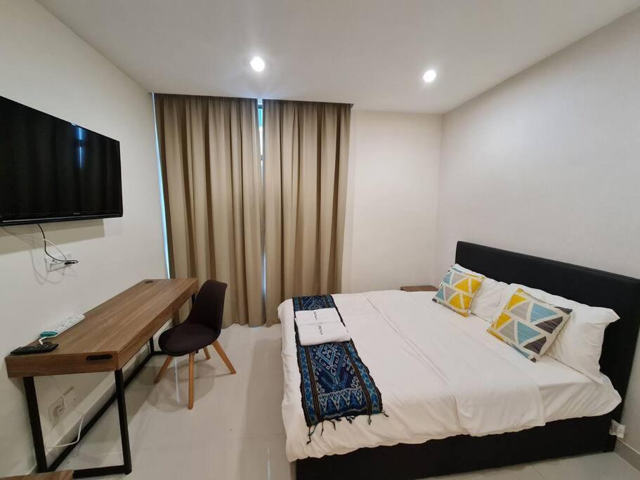 een slaapkamer met een bed, een bureau en een televisie bij Lovely Kozi Square comfort Studio Home 3B in Kuching