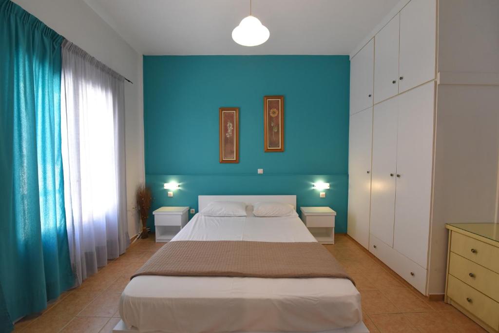 1 dormitorio con 1 cama grande y pared azul en Konstantza Studios and Apartments, en Ermoupoli
