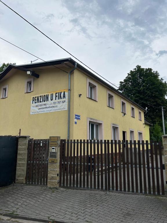 Penzion u Fika في أوسترافا: مبنى اصفر امامه سياج
