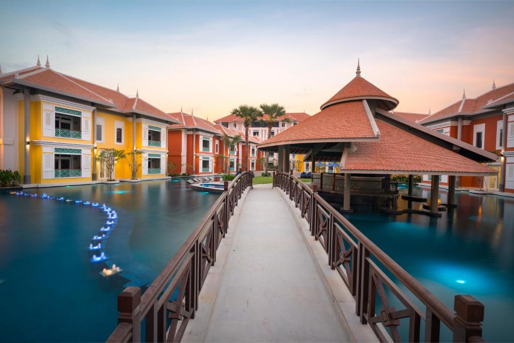 un ponte su un corpo idrico con edifici di Memoire Palace Resort & Spa a Siem Reap