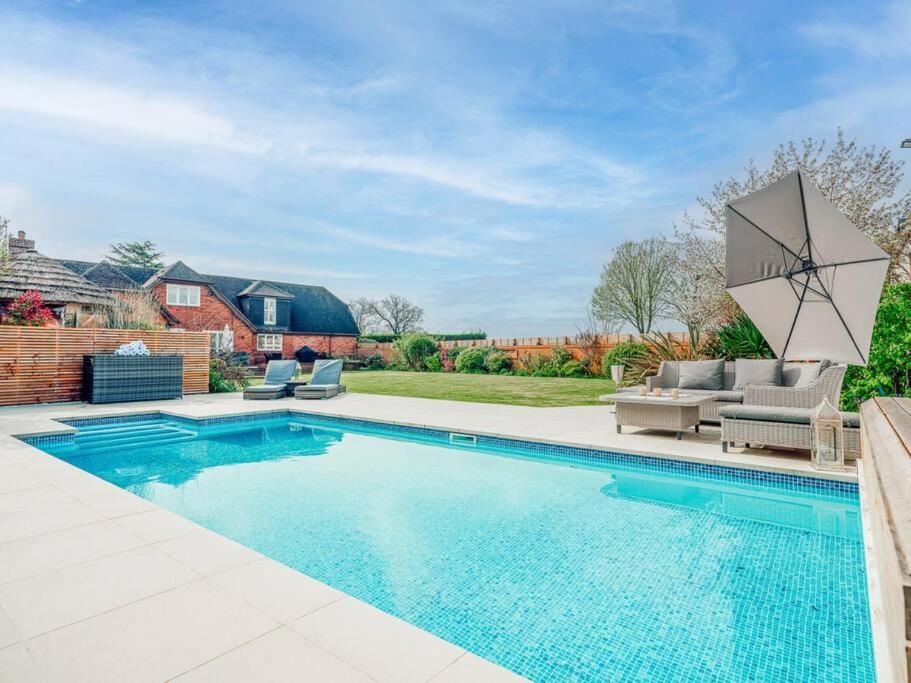 a swimming pool in a backyard with a patio furniture and a house at The Paddock - Luxury 5 Bed with Swimming Pool! in Ombersley