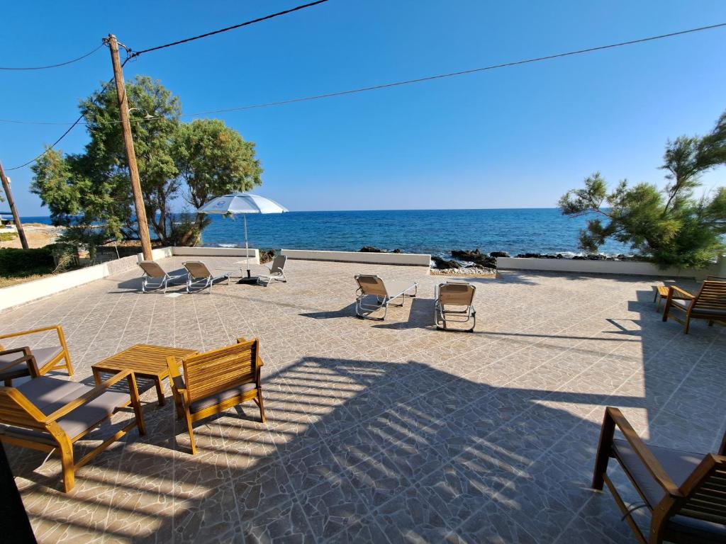 een patio met een tafel en stoelen en de oceaan bij Nettuno Seafront Apartments in Análipsis