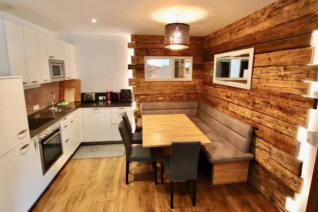 a kitchen and dining room with a wooden wall at Chalet Apartment Leogang in Leogang