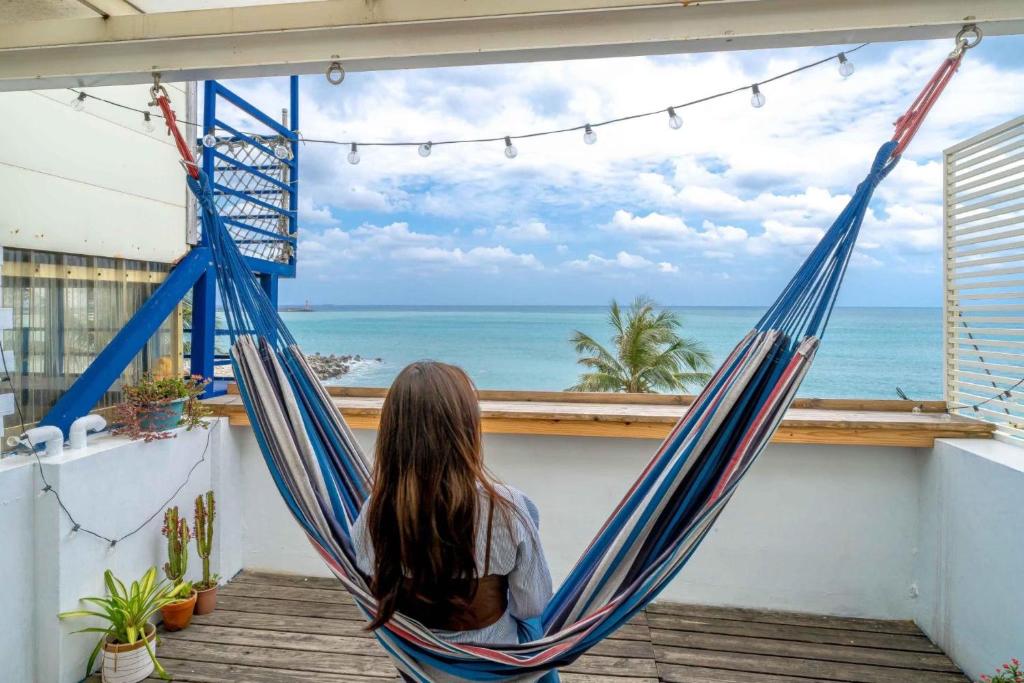 a woman sitting in a hammock looking out at the ocean at 花蓮包棟-聽海說故事海景民宿-東大門夜市旁 in Hualien City