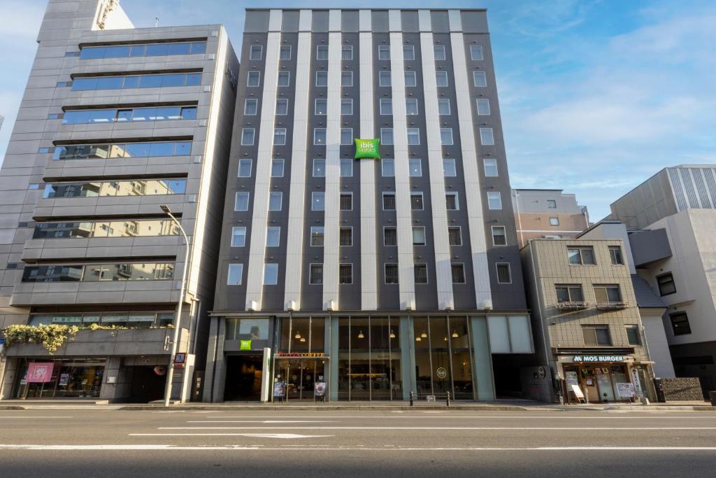 a tall building with a green sign on it at ibis Styles Kyoto Shijo in Kyoto