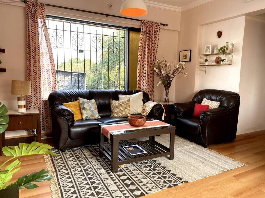 a living room with a leather couch and a table at Saba 301, Subko Coffee, Chapel Road, Bandra West by Connekt Homes in Mumbai