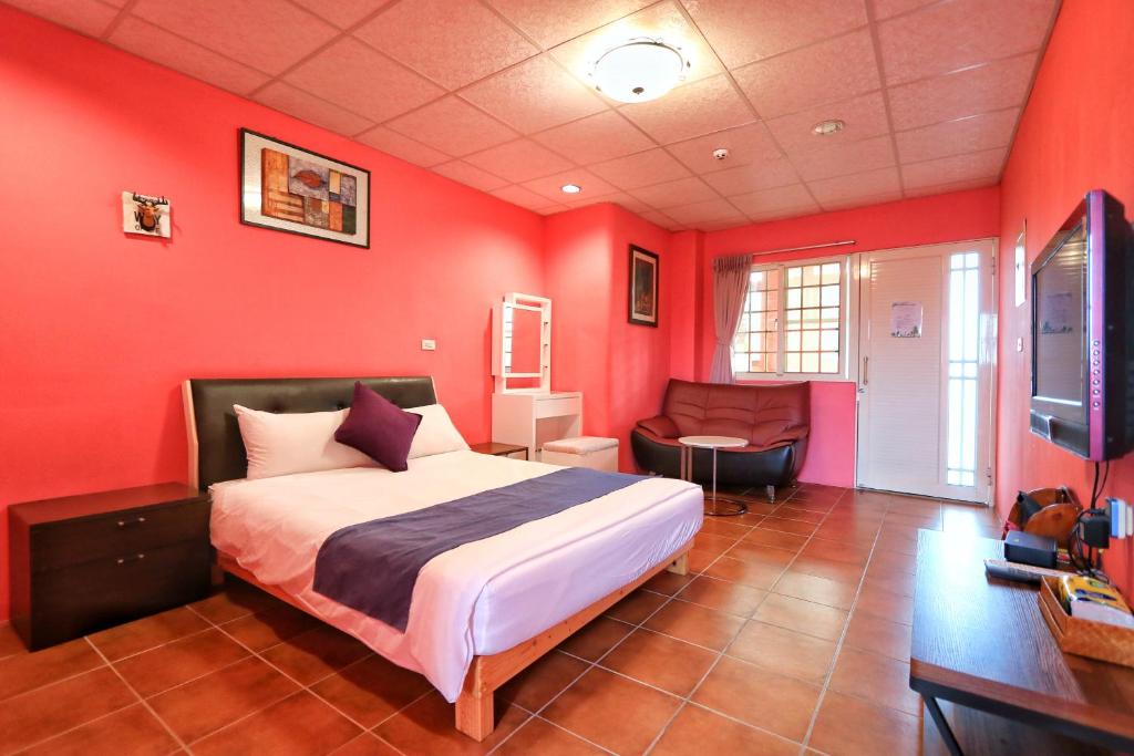 a bedroom with red walls and a bed and a desk at Fumigate Hotel in Hengchun South Gate